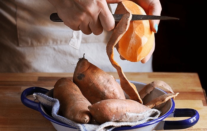 Person skinning sweet potatoes