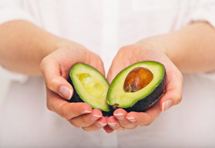Female hand holding sliced avocado